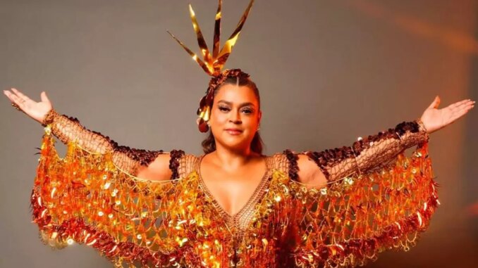 preta gil com roupas de carnaval e de braços abertos